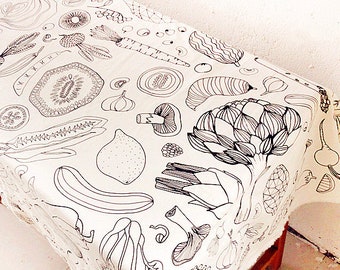 May include: A white tablecloth with a black and white line drawing pattern of various vegetables and fruits. The pattern includes artichokes, lemons, mushrooms, carrots, and kiwi.