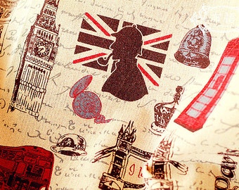 May include: A beige fabric with a vintage London theme. The fabric features a red, white, and blue Union Jack flag, a red double-decker bus, a clock tower, and a red telephone booth.