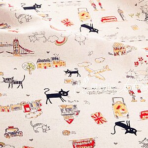 May include: Off-white fabric with a repeating pattern of black cats, London landmarks, and travel-themed illustrations. The design includes the Tower Bridge, Big Ben, airplanes, suitcases, and the Union Jack flag.