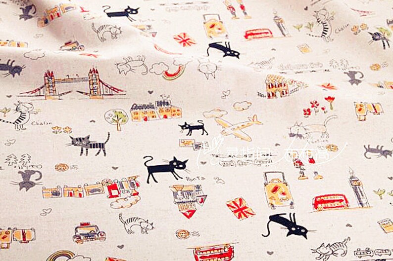 May include: Off-white fabric with a repeating pattern of black cats, London landmarks, and travel-themed illustrations. The design includes the Tower Bridge, Big Ben, airplanes, suitcases, and the Union Jack flag.