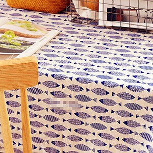 May include: A white tablecloth with a blue fish pattern. A wooden chair is in the foreground.