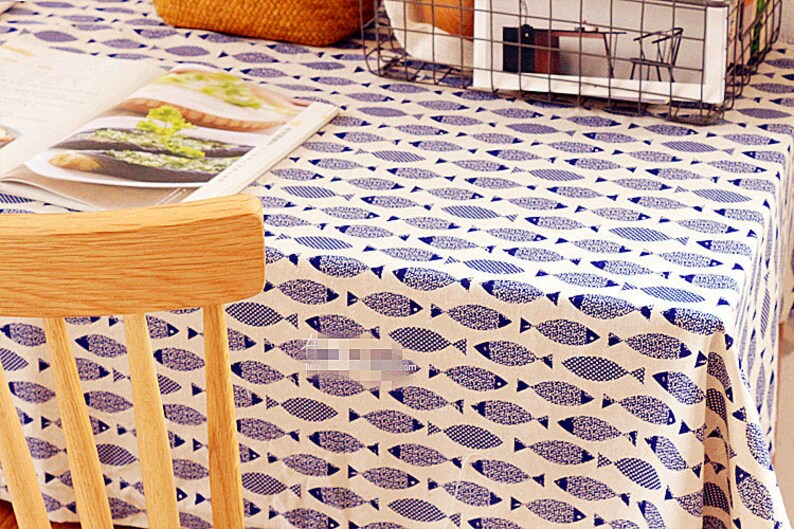 May include: A white tablecloth with a blue fish pattern. A wooden chair is in the foreground.