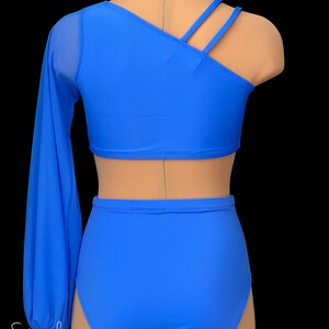 May include: A blue dance costume with a one-shoulder top and long sleeve, and high-waisted shorts. The top has a diagonal neckline and three straps across the back.
