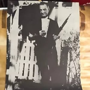 May include: Black and white photo of a man holding a rifle. The man is wearing a suit and tie. The photo is captioned "Gun Control Begins in the White House."