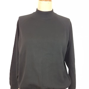 May include: A black sweater with a mock turtleneck collar and long sleeves. The garment is displayed on a mannequin against a white background. The sweater has a ribbed hem and cuffs.