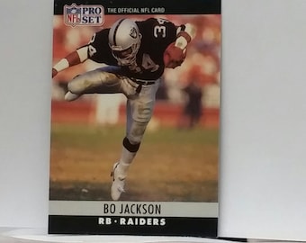 May include: A black and white NFL Pro Set trading card featuring a football player in a white uniform with the number 34 on the front. The player is running with the ball. The card has the text "PRO SET" and "THE OFFICIAL NFL CARD" at the top. The text "BO JACKSON RB - RAIDERS" is at the bottom of the card.