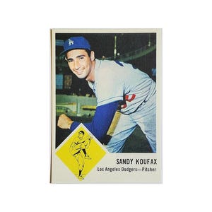May include: A vintage baseball card featuring Sandy Koufax, a pitcher for the Los Angeles Dodgers. The card is yellow and white with a picture of Koufax in his uniform and a smaller picture of him pitching in a diamond shape.