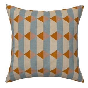 May include: Square cushion with a geometric pattern. The design features vertical stripes of light blue and beige, interspersed with rows of orange and pink triangles. The cushion has a textured appearance.