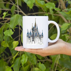 May include: White ceramic mug with a hand-drawn illustration of Cinderella's castle in a whimsical style.