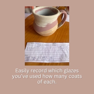 May include: A ceramic mug with a pink and white glaze. The mug is labeled "Snuggle" and has a chart listing the glazes used on the inside, bottom, middle, and top of the mug. The chart notes that the first layer is "old batch - new formula for coats 2 & 3".