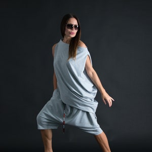 K&ouml;nnte beinhalten: Eine Frau tr&auml;gt ein locker sitzendes graues Outfit mit einer Kordeltaille und einem G&uuml;rtel, auf dem "LOVE LOVE LOVE" steht. Sie tr&auml;gt eine Sonnenbrille und hat ihr Haar offen.