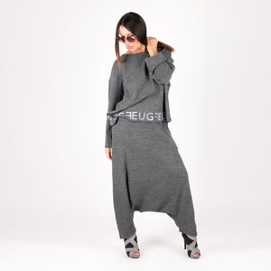 May include: A gray knit set with a loose-fitting top and wide-leg pants. The top has a band with the text "FEUGFEU" printed on it. The model is wearing the set with gray heeled sandals.