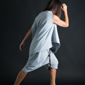 K&ouml;nnte beinhalten: Eine Frau tr&auml;gt ein graues, locker sitzendes, &auml;rmelloses Oberteil und passende Shorts. Die Shorts haben einen schwarzen und roten Kordelzug mit dem Wort "LOVE", das darauf wiederholt wird.