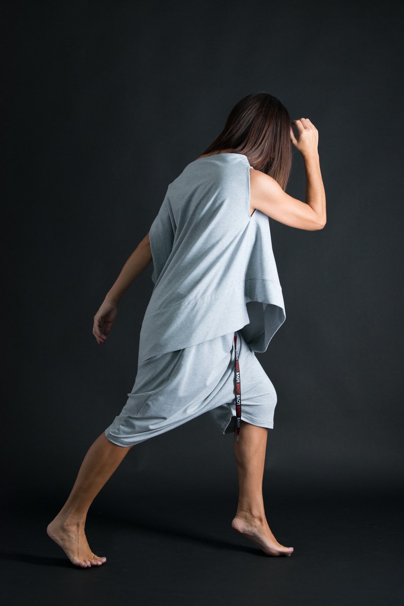 K&ouml;nnte beinhalten: Eine Frau tr&auml;gt ein graues, locker sitzendes, &auml;rmelloses Oberteil und passende Shorts. Die Shorts haben einen schwarzen und roten Kordelzug mit dem Wort "LOVE", das darauf wiederholt wird.