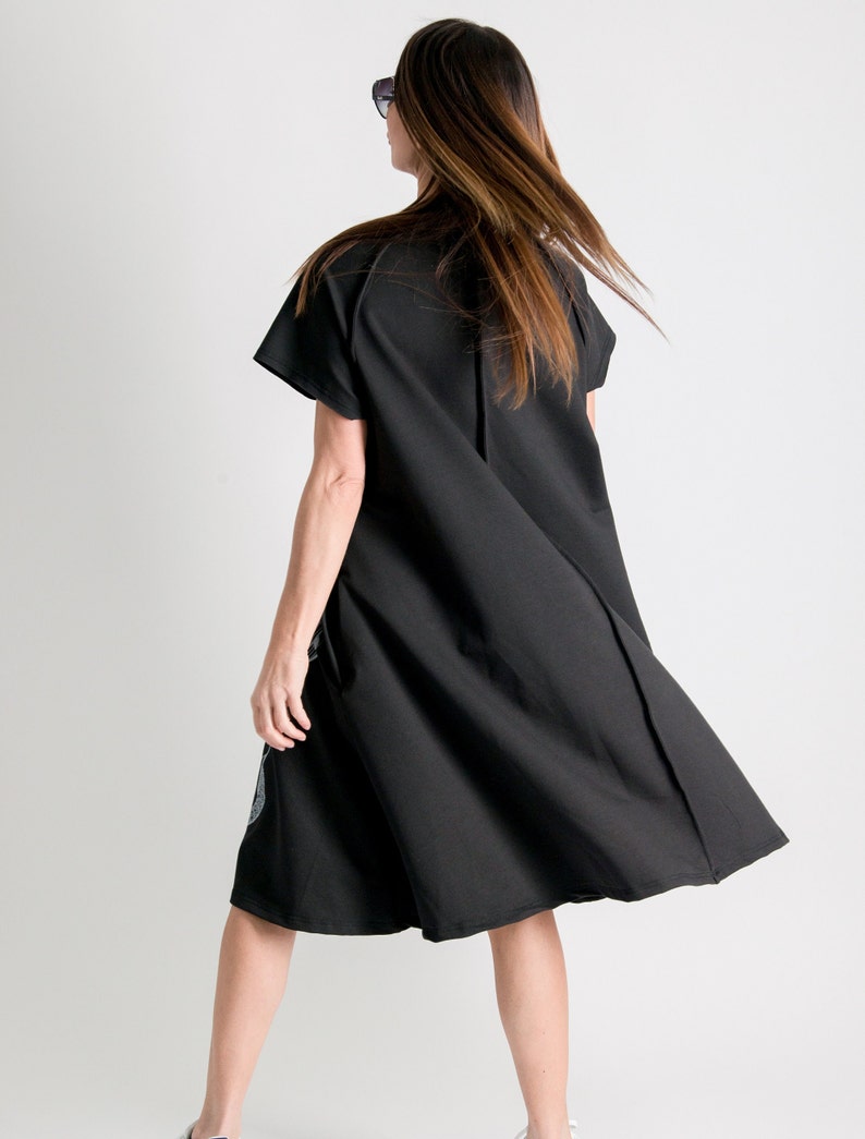 May include: A black short-sleeved dress with a loose fit and a flowing skirt. The dress is made of a soft, comfortable fabric.