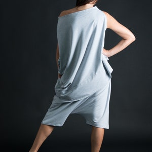 K&ouml;nnte beinhalten: Eine Frau tr&auml;gt einen locker sitzenden, hellgrauen Jumpsuit mit einem Schultertr&auml;ger und einem drapierten Design.