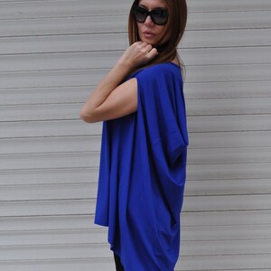 May include: A royal blue, loose-fitting, short-sleeved top with a draped neckline. The top is made of a soft, flowing fabric.