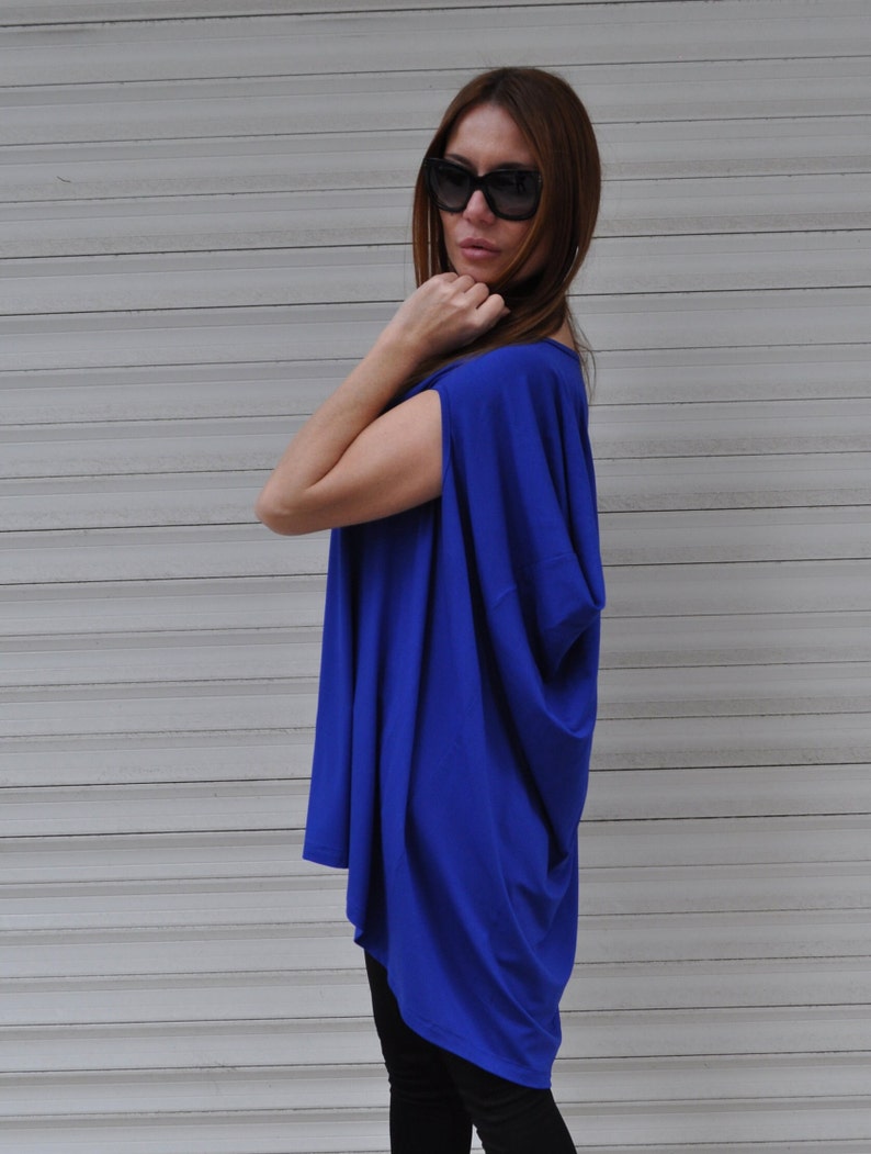 May include: A royal blue, loose-fitting, short-sleeved top with a draped neckline. The top is made of a soft, flowing fabric.
