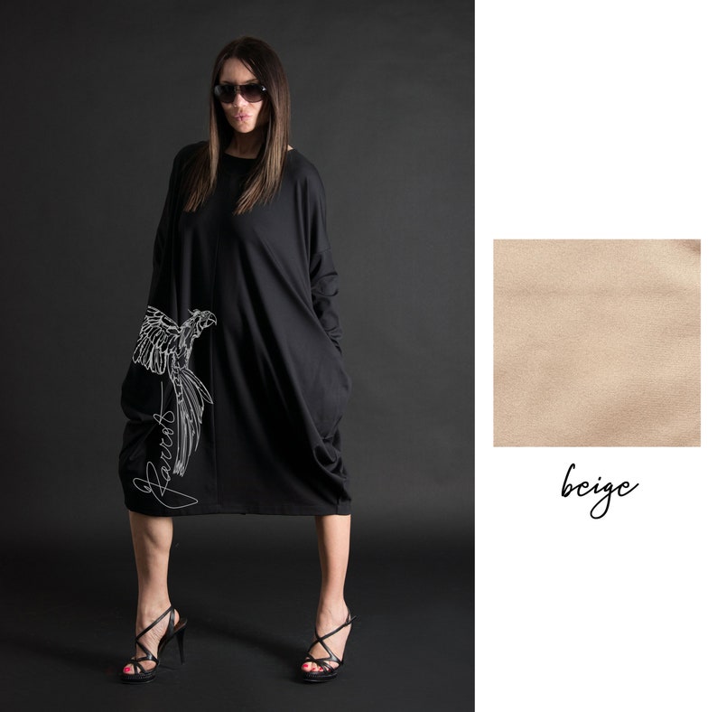 May include: Black oversized dress with long sleeves and a white parrot graphic on the side. The dress has a loose fit and a rounded hemline. The word "Parrots" is written in cursive below the parrot graphic.