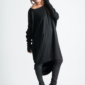 May include: A black long-sleeved tunic with a high-low hemline. The tunic is worn with black leggings and black high-heeled shoes.