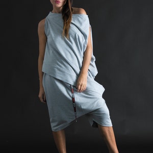 K&ouml;nnte beinhalten: Ein grauer, einseitiger, locker sitzender Jumpsuit mit einem schwarzen und roten "LOVE"-Druck an der Seite. Der Jumpsuit hat einen langen, flie&szlig;enden Rock und ein figurbetontes Oberteil.