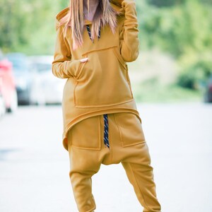 May include: A mustard yellow hooded sweatshirt and matching pants with a drawstring waist. The outfit is made of a soft, comfortable fabric and has a relaxed fit.