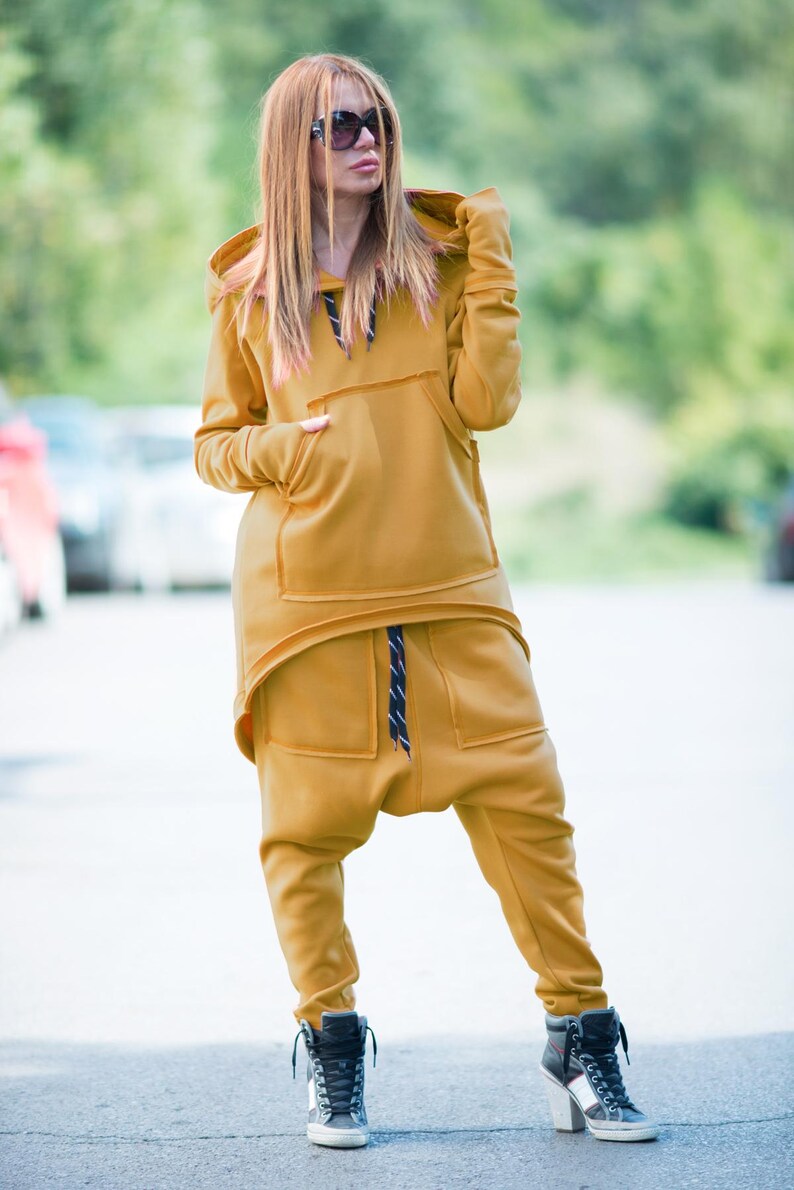 May include: A mustard yellow hooded sweatshirt and matching pants with a drawstring waist. The outfit is made of a soft, comfortable fabric and has a relaxed fit.