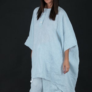 May include: A light blue linen tunic top with a button closure and a relaxed fit. The top is paired with matching light blue linen pants.