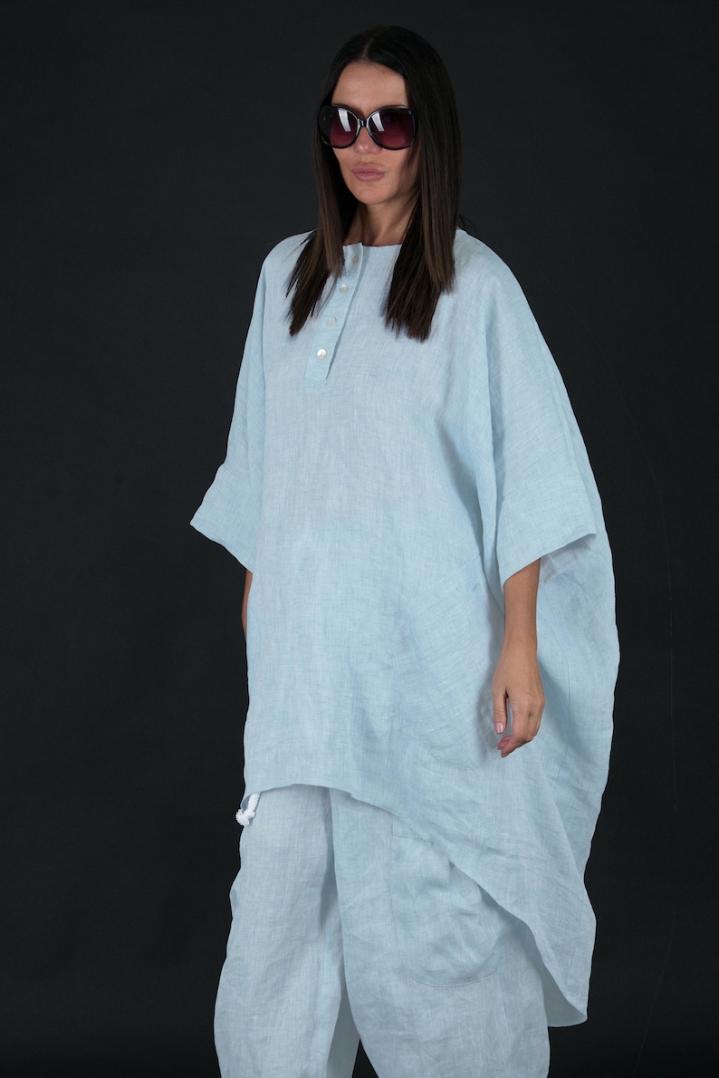 May include: A light blue linen tunic top with a button closure and a relaxed fit. The top is paired with matching light blue linen pants.