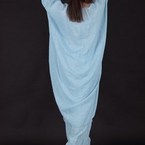 May include: A light blue linen jumpsuit with a loose, flowing fit. The jumpsuit has a wide leg and a gathered waist.