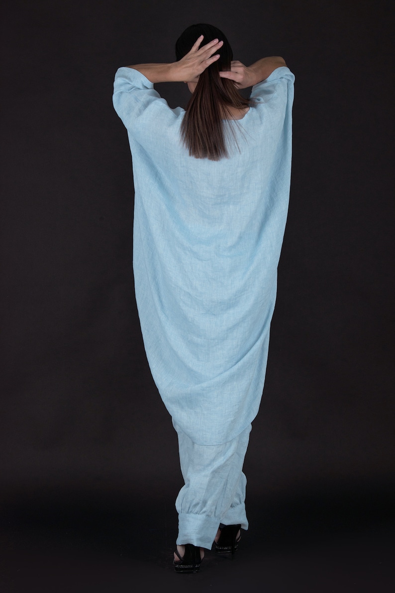 May include: A light blue linen jumpsuit with a loose, flowing fit. The jumpsuit has a wide leg and a gathered waist.