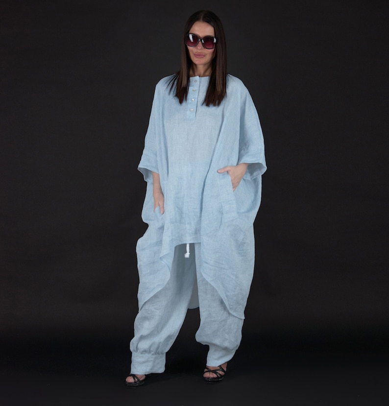 May include: A light blue linen tunic with a button closure and a drawstring at the waist. The tunic has a relaxed fit and is paired with matching light blue linen pants.