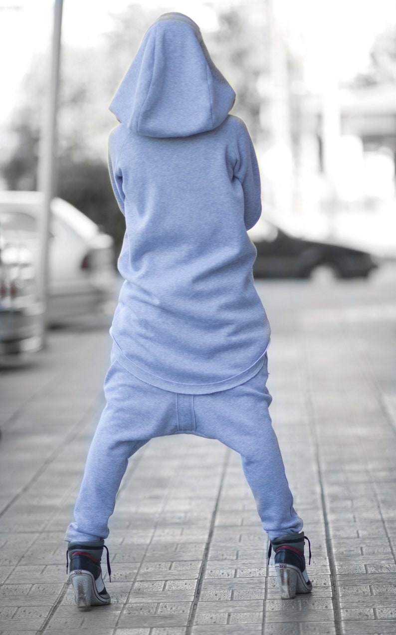 May include: A person wearing a light blue hooded sweatshirt and matching sweatpants. The person is standing on a brick walkway.