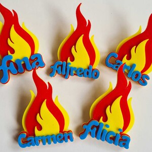 May include: Five flame-shaped decorations with names written in blue letters. The names are Ana, Alfredo, Carlos, Carmen, and Alicia.