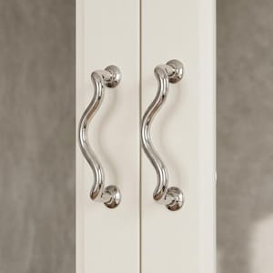 May include: Two polished chrome cabinet handles with a wavy, curved design. The handles are mounted on a white cabinet door, offering a modern and elegant aesthetic. The handles are symmetrical and have a smooth, reflective surface.