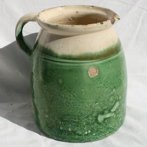 Könnte beinhalten: Ein grüner und weißer, glasierter Keramik Krug mit Henkel. Der Krug hat ein rustikales, Vintage- Aussehen.