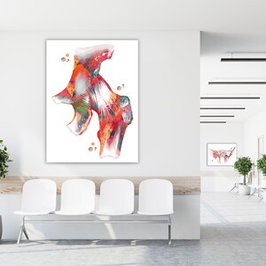 May include: A large, rectangular watercolor print of a hip joint, showcasing a vibrant mix of red, orange, green, and white hues. The artwork is displayed on a white wall in a waiting room setting, with white chairs and a plant.