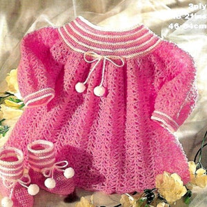 Peut inclure: Une robe de bébé en crochet rose avec des bordures blanches et un nœud au niveau de l'encolure. La robe a un ourlet festonné et est assortie à des chaussons en crochet rose et blanc. La robe mesure 21 pouces de long et 46 cm de circonférence.