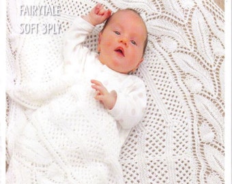 May include: A baby wrapped in a white knitted shawl with a delicate openwork pattern. The shawl is labeled "Fairytale Soft 3ply" and "Knitted Shawl...an Heirloom Class". The baby is wearing a white onesie.