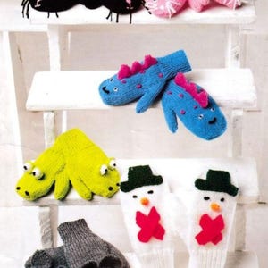 Op de afbeelding: Een collectie gebreide wanten met dierenthema, waaronder zwarte katten, roze konijnen, blauwe dinosaurussen met roze stekels, limoengroene krokodillen, witte sneeuwpoppen met groene hoeden en rode strikken, en grijze muizen met gedetailleerde gezichten.