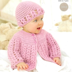 May include: A pink crocheted cardigan and matching hat for a baby. The cardigan has a button closure and a delicate stitch pattern.