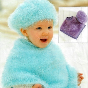 May include: A baby wearing a light blue fuzzy knitted poncho and matching beret. The poncho and beret are both made with a fluffy yarn.