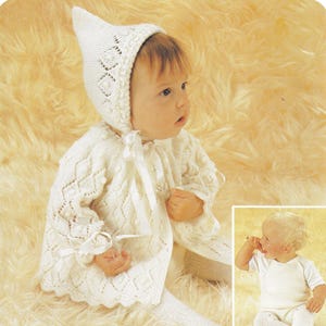 May include: A baby wearing a white knitted outfit, including a bonnet, cardigan, and leggings. The outfit features a diamond pattern and is tied with white ribbons. A smaller image shows a baby in a white onesie and leggings.