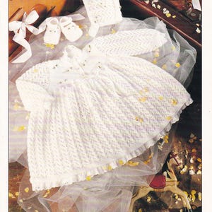 Può includere: Un set lavorato a maglia bianco per neonati composto da vestito, cuffietta e scarpine con un motivo testurizzato. La confezione del modello riporta il testo DOUBLE KNITTING, 16-22" 41-56cm, 3665 e SIRDAR. I capi hanno maniche lunghe e orlo arricciato.