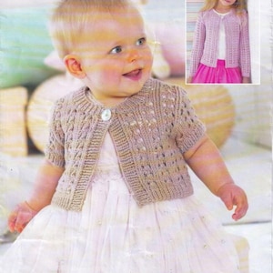 Può includere: Un bambino indossa un cardigan lavorato a maglia marrone chiaro a maniche corte con una chiusura a bottone singolo. Il cardigan ha un motivo strutturato ed è abbinato a un vestito bianco. Un'immagine più piccola mostra una ragazza con un cardigan rosa simile.
