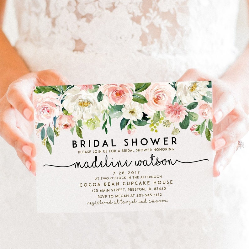 May include: A white card with pink and white floral border. The text reads "Bridal Shower" and "Please join us for a bridal shower honoring Madeline Watson". The date is 7.28.2017, the time is 2 o'clock in the afternoon, and the location is Cocoa Bean Cupcake House, 123 Main Street, Preston, ID, 83440. RSVP to Megan at 201-545-1122. Registered at Target and Amazon.