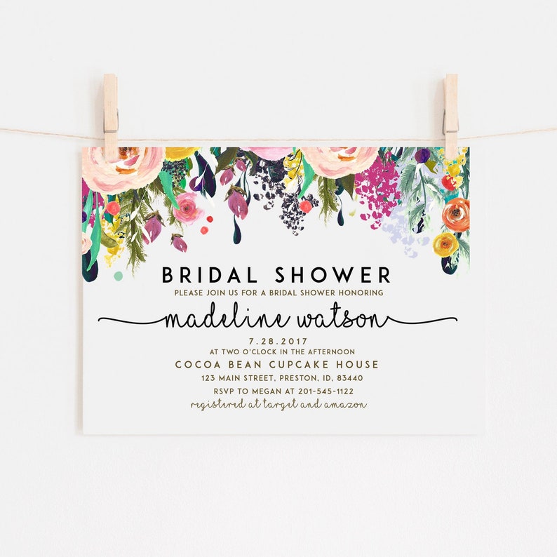 May include: A floral bridal shower invitation with a watercolor design. The invitation features a colorful floral garland with dripping paint and the text "BRIDAL SHOWER" in black. The bride's name, "madeline watson", is written in cursive script. The date, "7.28.2017", is written in black. The location, "COCOA BEAN CUPCAKE HOUSE", is written in black. The address, "123 MAIN STREET, PRESTON, ID, 83440", is written in black. The RSVP information, "RSVP TO MEGAN AT 201-545-1122", is written in black. The registry information, "registered at target and amazon", is written in black.