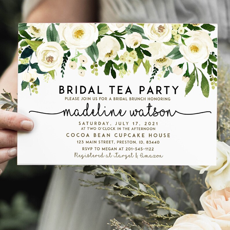 May include: Bridal tea party invitation with white flowers and greenery. The invitation reads "Bridal Tea Party" and "Please join us for a bridal brunch honoring Madeline Watson". The date is Saturday, July 17, 2021 at two o'clock in the afternoon. The location is Cocoa Bean Cupcake House, 123 Main Street, Preston, ID, 83440. RSVP to Megan at 201-545-1122. Registered at Target & Amazon.