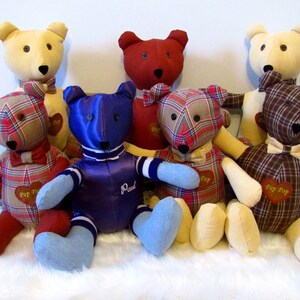 May include: Seven handmade teddy bears with plaid fabric and bow ties. The bears are sitting on a white fluffy surface. The bears are all different colors and have different names embroidered on them.