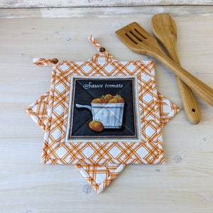 Peut inclure: Une manivelle de pot en tissu matelassé orange et blanc avec un motif carré et une image d'un pot blanc rempli de tomates. Le texte "Sauce tomate" est imprimé sur l'image.